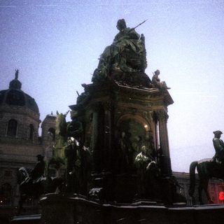 Equestrian statue with historical figures, illuminated at night.