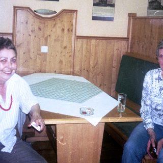 Two women sitting indoors in 1985, smiling at a table.