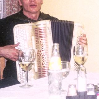 Two men enjoying drinks and music indoors.