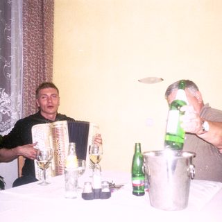 Two men enjoying drinks and music indoors.