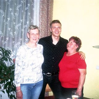 Three people smiling indoors during a gathering.