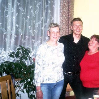 Three people smiling indoors during a gathering.