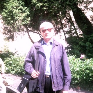 Two people walking outdoors in a garden setting.