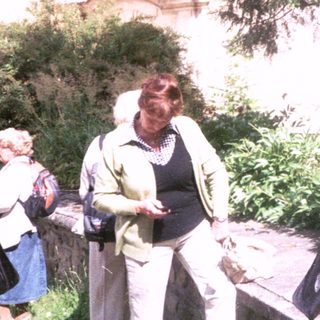 Two people walking outdoors in a garden setting.