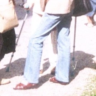 Elderly couple walking outdoors with mobility aid.