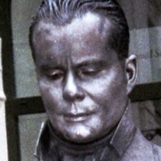 Bronze statue of a man in vintage suit holding umbrella.