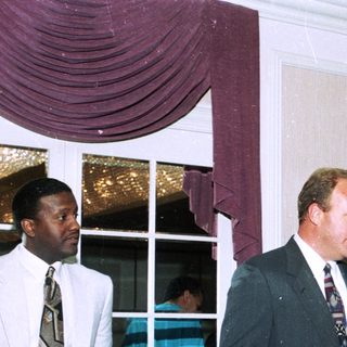 Men speaking at an indoor formal event.