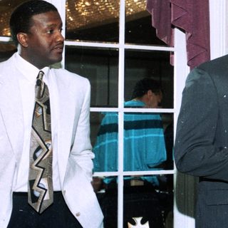 Men speaking at an indoor formal event.