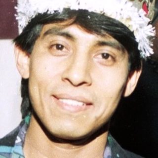 Man in formal suit wearing festive party hat.