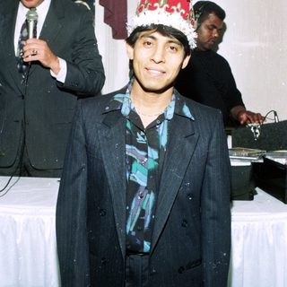 Man in formal suit wearing festive party hat.