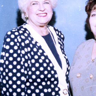 Three women posing together in formal attire.