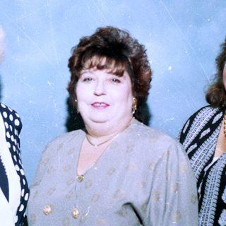 Three women posing together in formal attire.