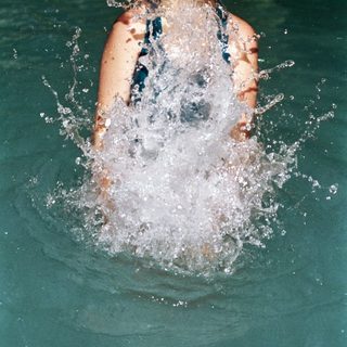 Girl joyfully splashing water in swimming pool.