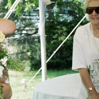 Couple embracing under tent at outdoor wedding.