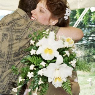 Couple embracing under tent at outdoor wedding.