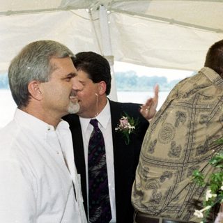 Couple embracing under tent at outdoor wedding.