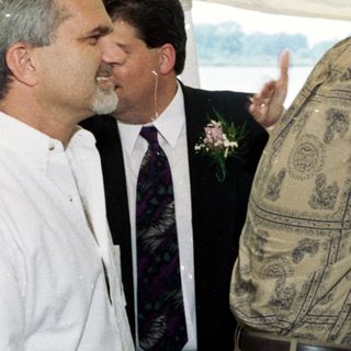 Couple embracing under tent at outdoor wedding.