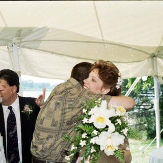 Couple embracing under tent at outdoor wedding.