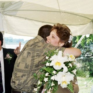 Couple embracing under tent at outdoor wedding.