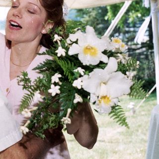 Joyful older man hugging woman holding bouquet.