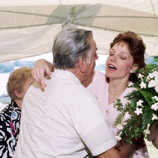 Joyful older man hugging woman holding bouquet.