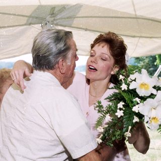 Joyful older man hugging woman holding bouquet.