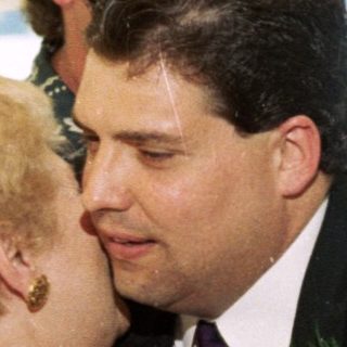 Wedding ceremony with groom kissing bride's cheek.