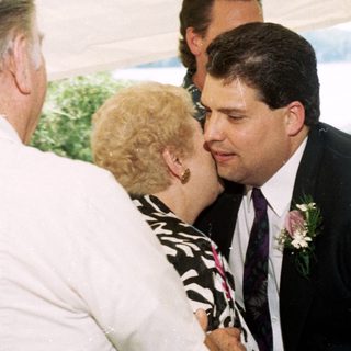Wedding ceremony with groom kissing bride's cheek.