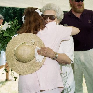 Emotional farewell hug between two women at outdoor gathering.