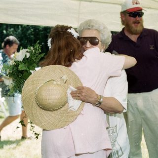 Emotional farewell hug between two women at outdoor gathering.