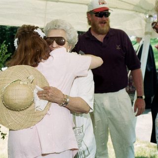 Emotional farewell hug between two women at outdoor gathering.