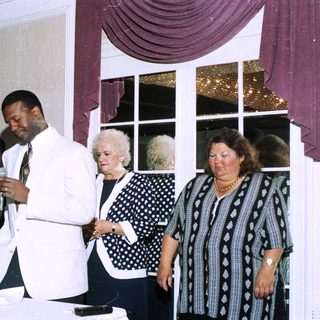 Group at indoor event, man speaking into microphone.