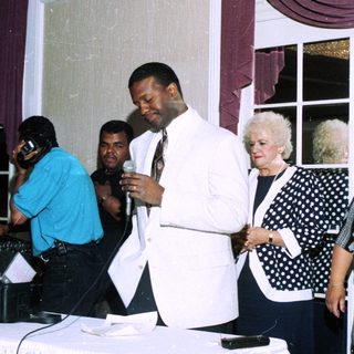 Group at indoor event, man speaking into microphone.