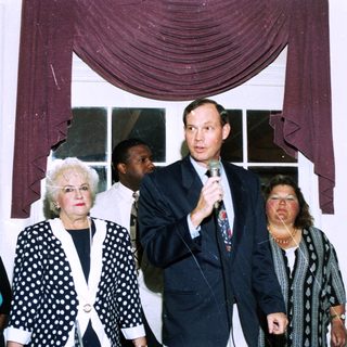 People at indoor event speaking into microphone.