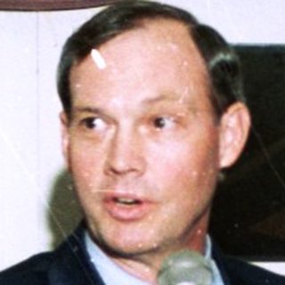 People at indoor event speaking into microphone.