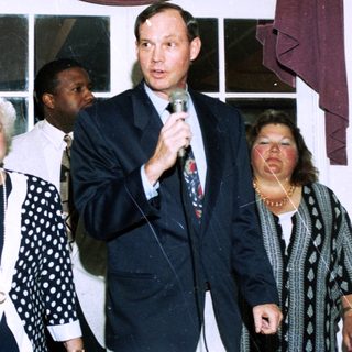 People at indoor event speaking into microphone.