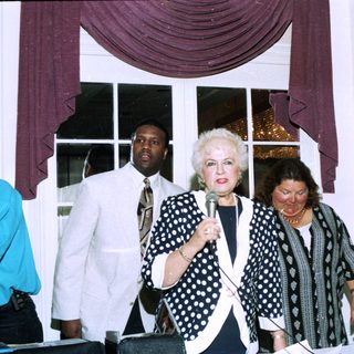 Three women speaking at an indoor event.