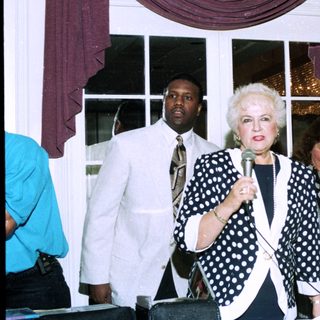 Three women speaking at an indoor event.