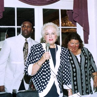 Three women speaking at an indoor event.