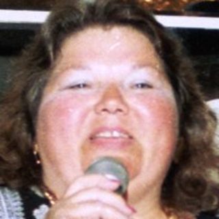 Woman speaking at indoor event with microphone.