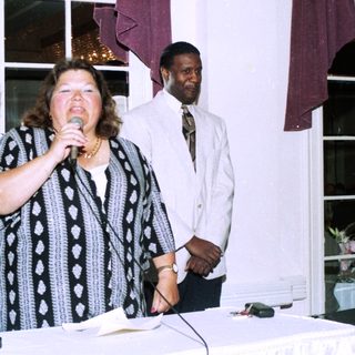 Woman speaking at indoor event with microphone.