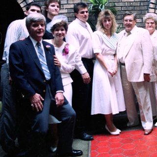 Group of people posing formally outdoors near archway.