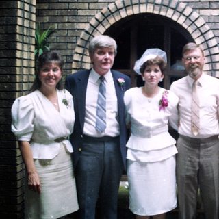 Group posing in formal attire at wedding.
