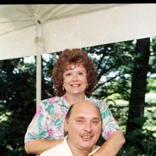 Happy couple posing outdoors under tent.