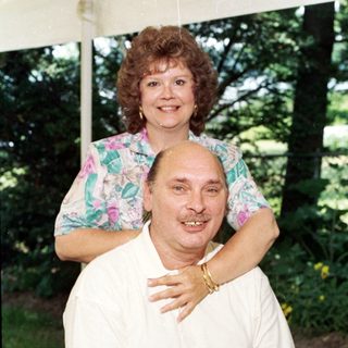Happy couple posing outdoors under tent.