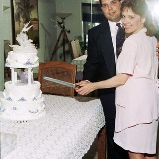 Couple cutting wedding cake indoors.