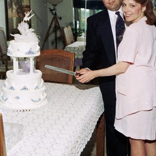 Couple cutting wedding cake indoors.