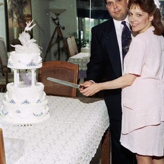 Couple cutting wedding cake indoors.