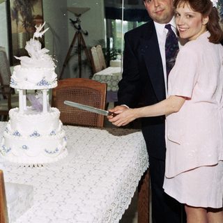 Couple cutting wedding cake indoors.