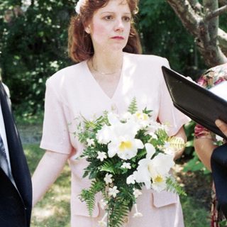 Wedding ceremony with bride, groom, officiant, and guests outdoors.